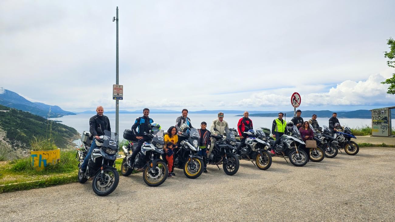 MotoRover tour group lined up with their motorcycles at a coastal viewpoint overlooking the Adriatic Sea.