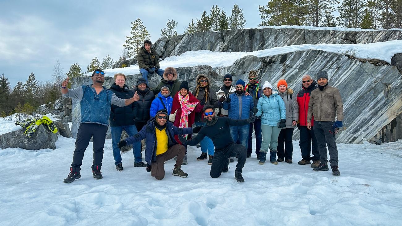 Tour group posing for a photo in front of striking grey marble rock formations at a snow-covered quarry in Karelia.